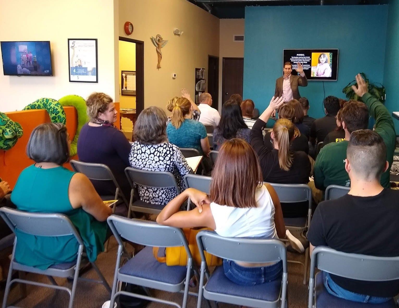 A packed workshop with attendees raising their hands